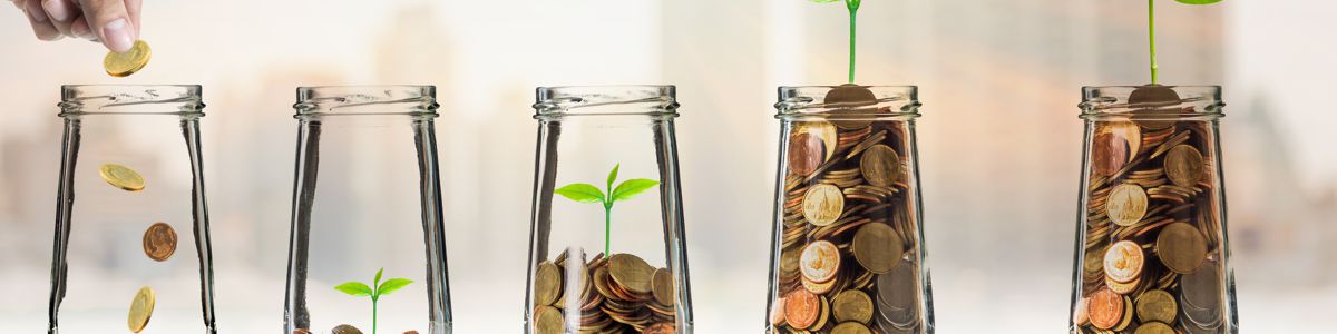 Building Wealth – Simple, Not Easy - Gold coins in glass jars at Alman Partners True Wealth Mackay